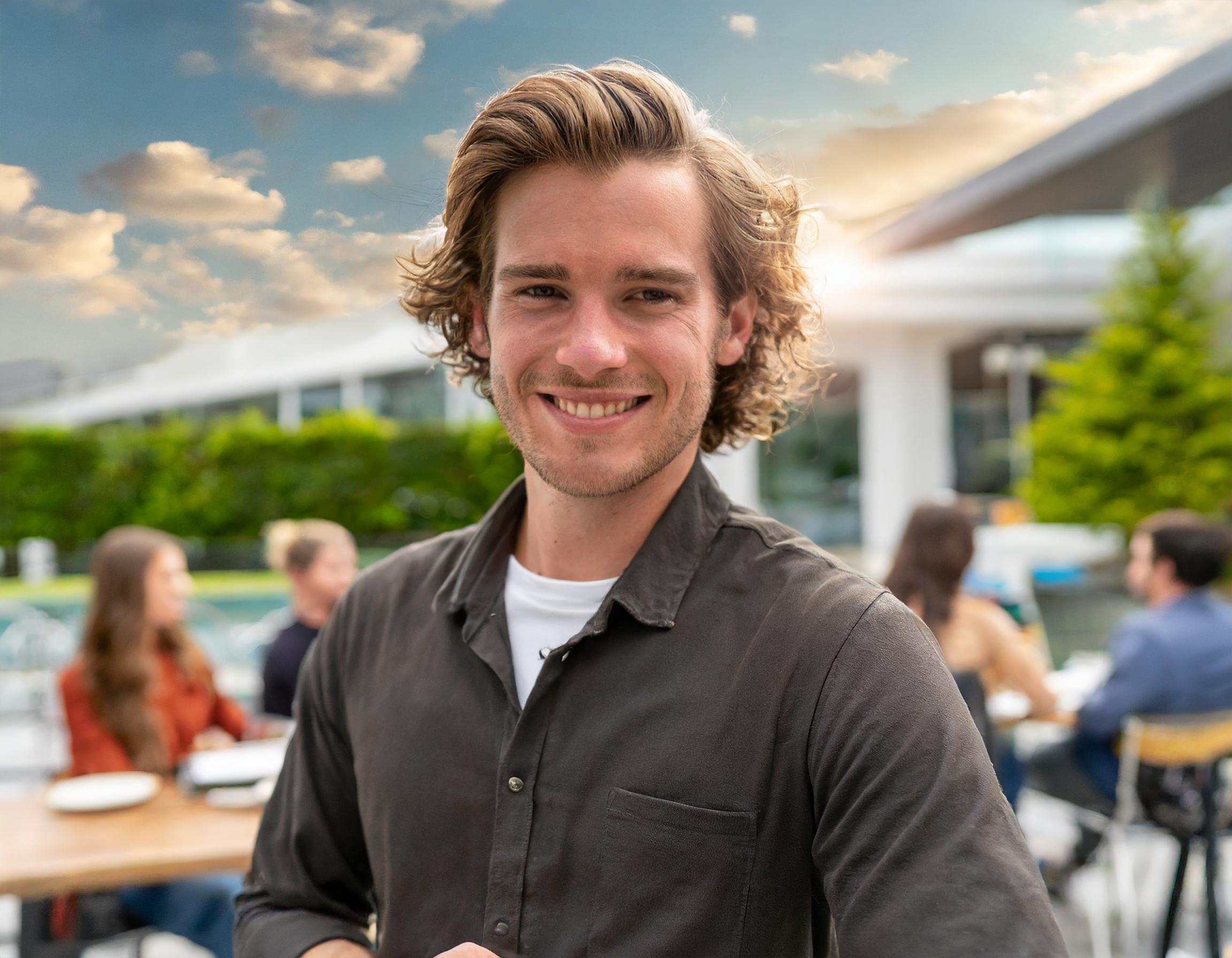 Lächelnder Mann in einem Burger-Restaurant, leger gekleidet, mit Kreativ-Brille